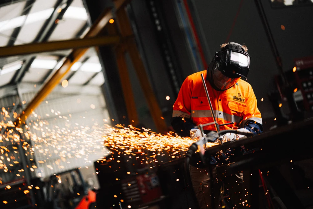 Baxter engineer grinding steel with sparks flying